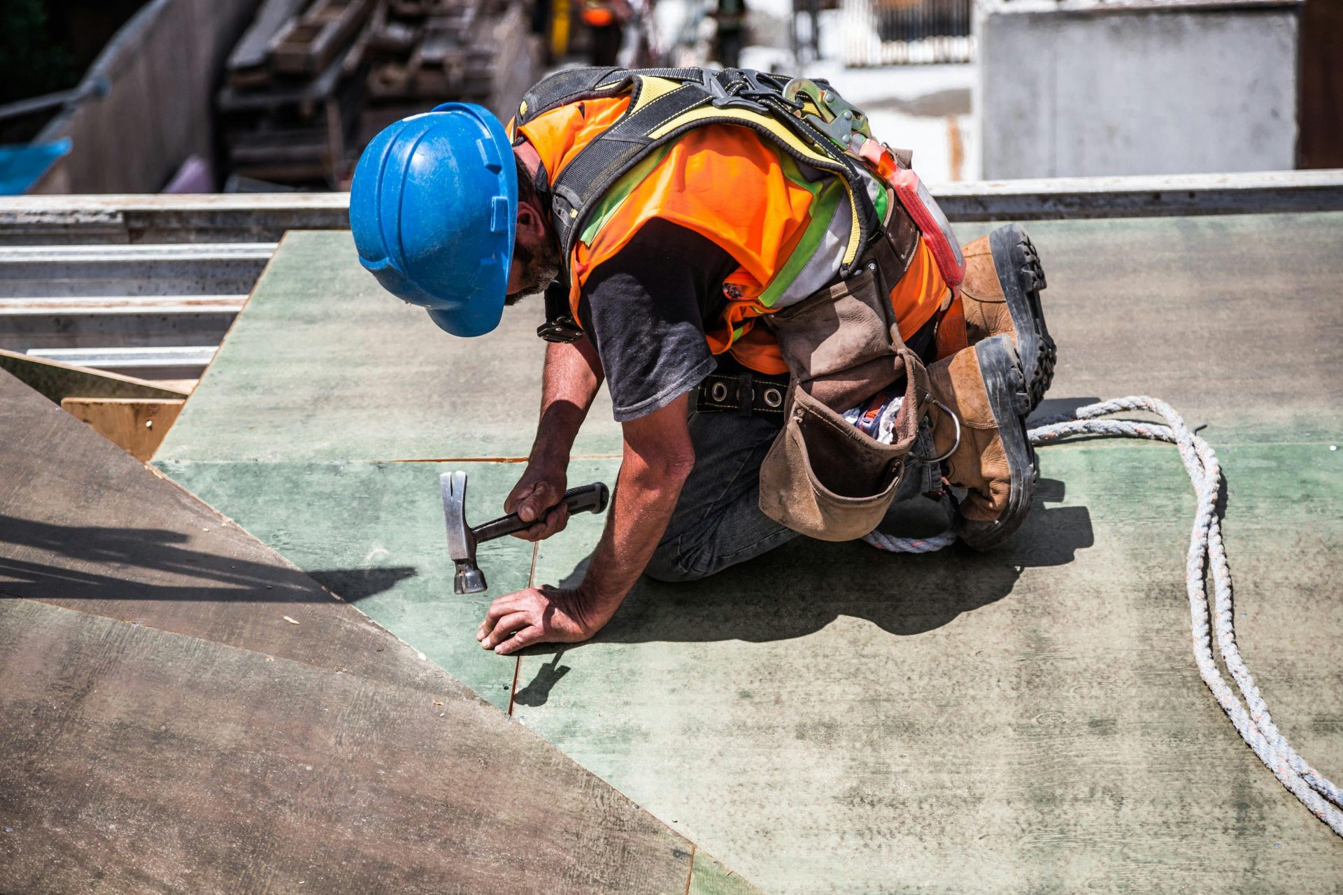 Un obrero de la construcción cualificado, con equipo de protección, martilla un panel del tejado.